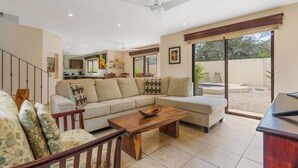 A spacious living area with a sofa, coffee table, and a view of the backyard. - Casa Luz de Luna (Tempate)