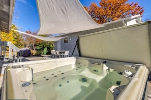 Un bain à remous doté d’un auvent, entouré de mobilier d’extérieur et d’un petit bâtiment.