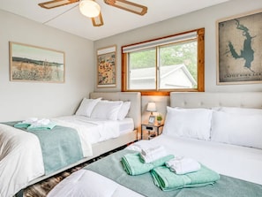 Une chambre d’hôtel avec deux lits, une grande fenêtre, une carte accrochée au mur et un ventilateur de plafond.