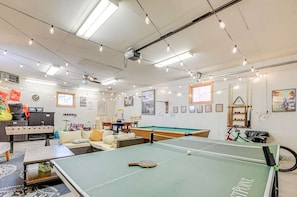 Une pièce équipée d’une table de ping-pong, d’un canapé, d’une petite table de billard et de divers équipements sportifs.