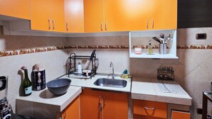 A kitchen with orange cabinets, a sink, a stove, and various kitchen utensils. - Bright and comfortable apartment close to Real Plaza - Pet friendly (Cusco)