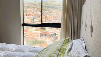 Ein Hotelzimmer mit Bett, einem Fenster und Blick auf die Stadt sowie einem Vorhang.
