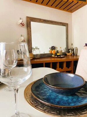 A table with a wine glass, a decorative bowl, and a mirror reflecting a room with a wooden ceiling and various items on a shelf. - Bright and comfortable apartment close to Real Plaza - Pet friendly (Cusco)