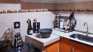 Une cuisine avec des meubles de rangement orange, un mixeur, une bouilloire et un évier.