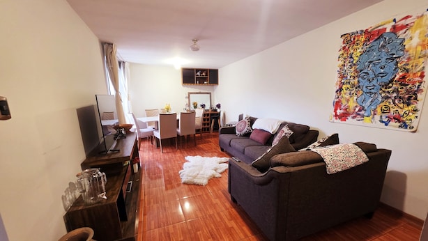 A modern living room with a sofa, coffee table, and a dining area with chairs and a table. - Bright and comfortable apartment close to Real Plaza - Pet friendly (Cusco)