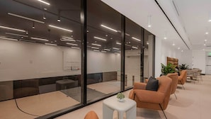 A modern waiting area with glass partitions, leather seating, a small table with a plant, and a visible reception desk. - Maison 225 | Downtown Miami Luxe Retreat (Miami)