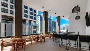 A modern bar area with high tables and chairs, large windows offering city views, and a contemporary interior design. - Maison 225 | Downtown Miami Luxe Retreat (Miami)