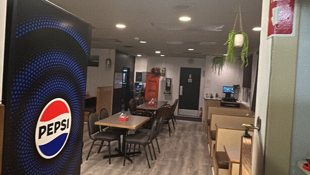 A restaurant with a Pepsi refrigerator, tiled flooring, and a counter with a computer monitor. - Barnays Motel (Letellier)