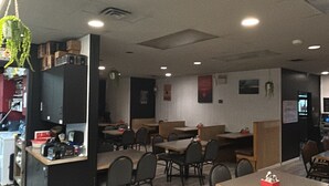 A restaurant with booths and tables, a kitchen area, and a counter. - Barnays Motel (Letellier)