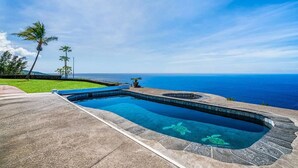 A swimming pool with a clear view of the ocean and a tropical landscape. - Kona Ocean Paradise with Pool and Hot Tub (Captain Cook)