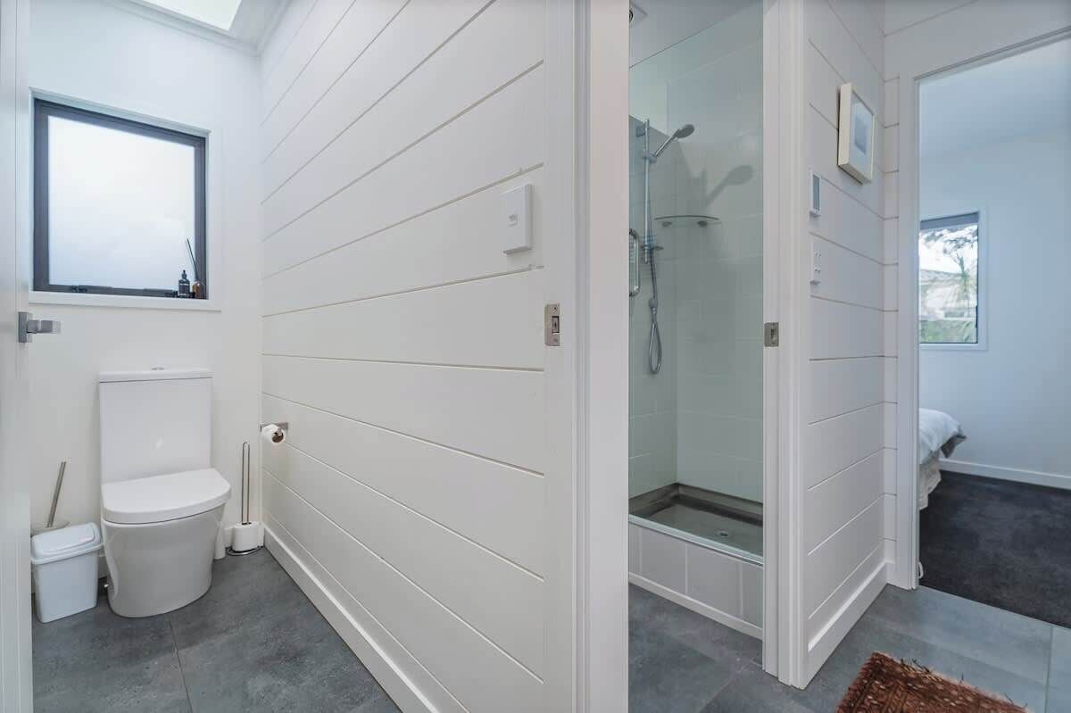 Een moderne badkamer met toilet, hygiëneschuimer en douche.