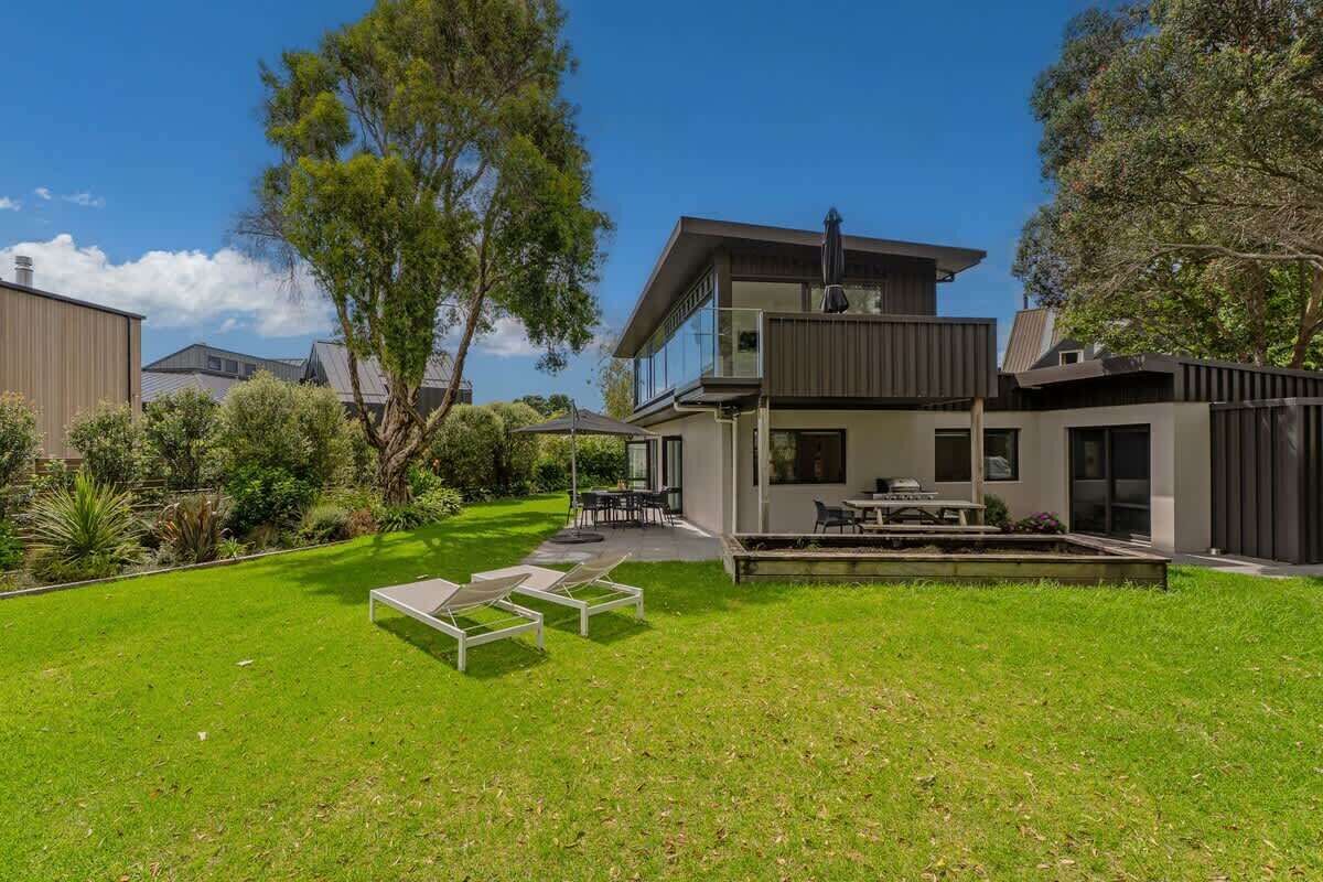 Et moderne hus på to etager med en rummelig baghave, en terrasse med udendørs møbler og en velplejet græsplæne.