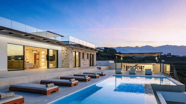 Una casa moderna con piscina, area relax esterna e vista sulle montagne.