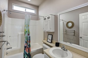 A bathroom with a bathtub, toilet, sink, and a shower curtain.