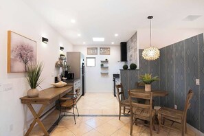 A modern kitchen with a dining area, featuring a wooden table, chairs, and a hanging light fixture. - Private Central Studio · Near Beverly Hills (Beverly Hills)