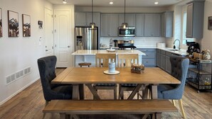 Una cocina moderna con armarios grises, una isla central, electrodomésticos de acero inoxidable e iluminación colgante.