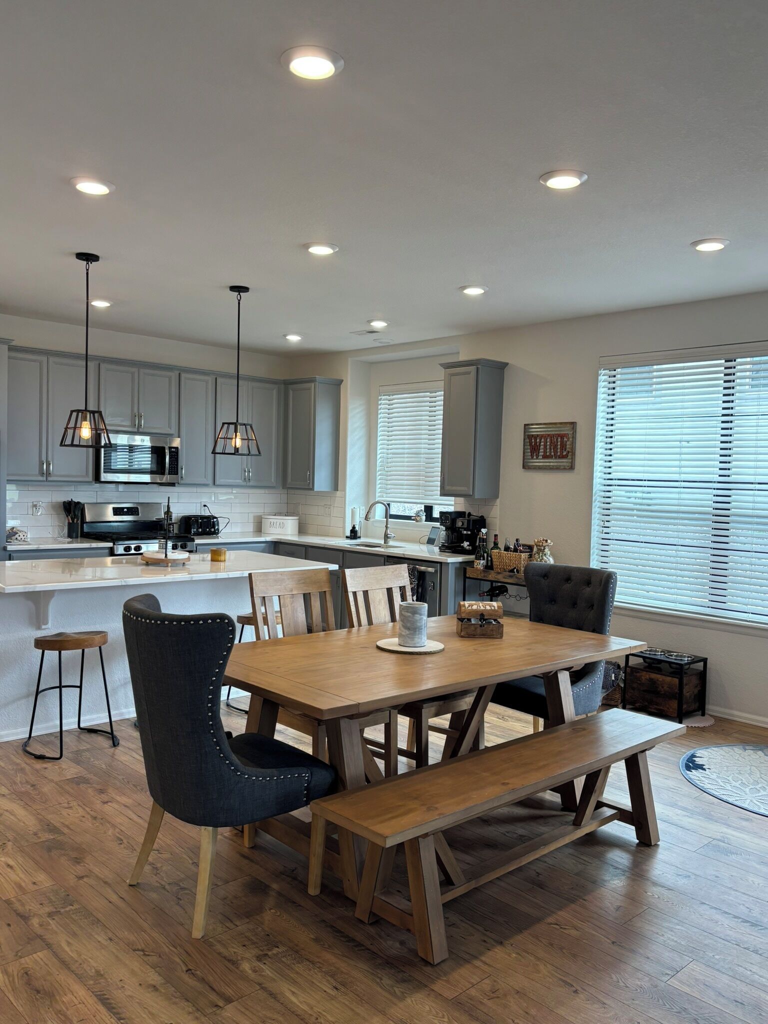 Una cocina moderna con una isla central, mesa de comedor de madera y taburetes de bar.
