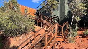 Eine Holztreppe führt zu einem Gebäude mit grüner Fassade.