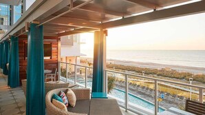 Ein Balkon mit Korbmöbeln, einem Pool und Blick auf den Strand.