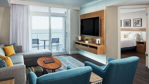 Ein modernes Hotelzimmer mit großem Fenster, Flachbildfernseher, einer Couch, einem Couchtisch und einem Bett.