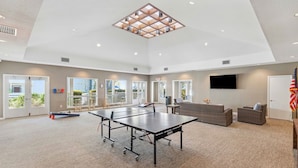 Un espace intérieur spacieux comprenant une table de ping-pong, des sièges et une grande fenêtre laissant entrer la lumière naturelle.