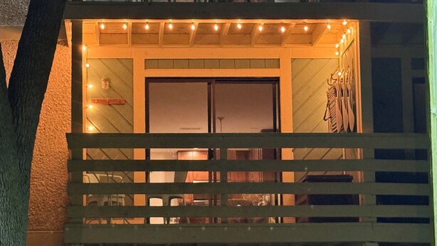 Un bâtiment à la façade en bois, doté d’un balcon avec une balustrade et illuminé de guirlandes lumineuses.