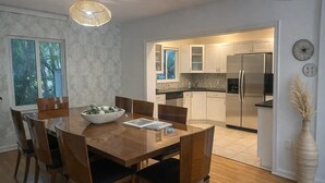 Eine moderne Küche mit weißen Schränken, einem Edelstahl-Kühlschrank und einem Essbereich mit Holztisch und Stühlen.