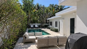 Ein Garten mit Pool, Korbmöbeln und Grill.