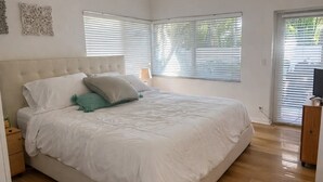Ein Schlafzimmer mit einem großen Bett, zwei Nachttischen und einer TV-Konsole mit Fernseher.