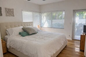 A bedroom with a large bed, two bedside tables, and a TV stand with a TV. - Private Tropical Oasis w/Pool in Prime West Palm Beach (West Palm Beach)
