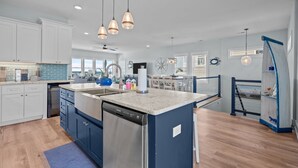 A spacious kitchen with white cabinets, a central island, and pendant lighting. - Ocean Views with Heated Pool! One Row from Beach! (Oak Island)