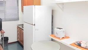 Une cuisine compacte équipée d’un réfrigérateur, d’un grille-pain et d’une petite table à manger.