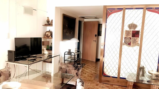 Un salon moderne avec une table à manger en verre, des sièges confortables, un téléviseur à écran plat et une porte en bois décorative.