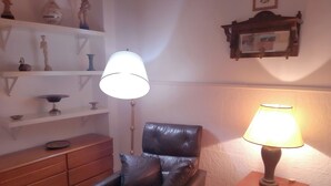 Un salon avec un fauteuil en cuir, un meuble en bois et une lampe sur pied.