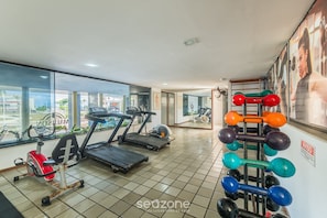A gym with treadmills, a stationary bike, and a dumbbell rack. - Fully Equipped Apartments in a Building With Pool, 40 m From the Beach in Salvador Mpas (Salvador)