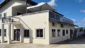 Un bâtiment moderne à deux étages, doté d’un balcon couvert et d’un escalier menant à l’étage supérieur.