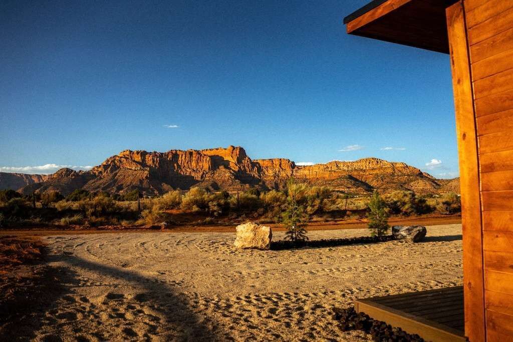 A wooden cabin with a view of a desert landscape and mountains.
