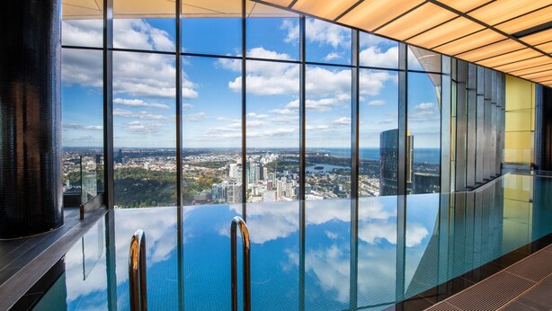 Piscina interior moderna con una vista panorámica de la ciudad a través de amplias ventanas.