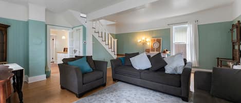 A spacious living room with two grey sofas, a patterned rug, and a staircase leading to another room.