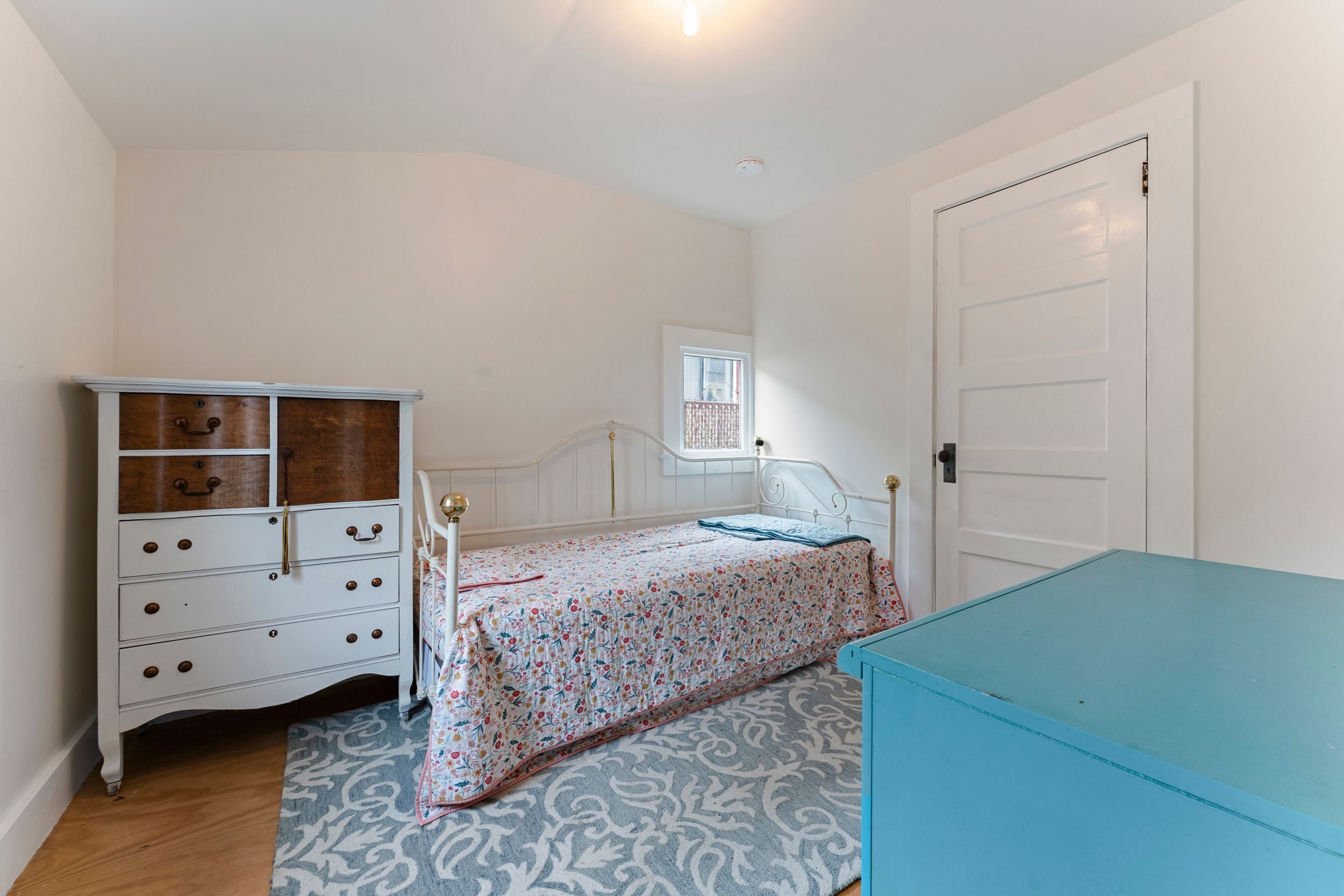 Une chambre à coucher avec un lit, une commode et un placard bleu.