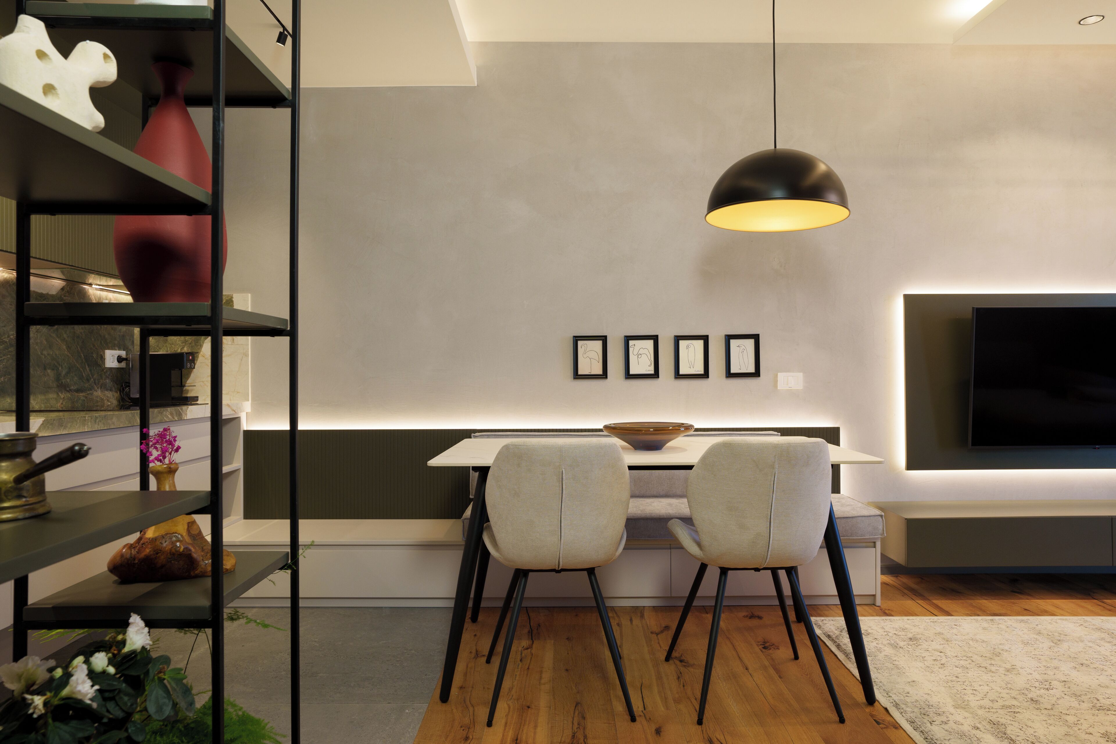 A modern dining area with a white table, two chairs, a bowl, and a pendant light.
