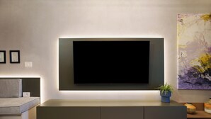 Ett modernt vardagsrum med en platt-TV som är monterad på väggen, en inbyggd bänk under och en tavla på väggen.