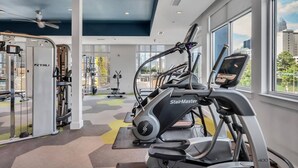 Ett gym med löpband, styrketräningsmaskiner och en takfläkt.