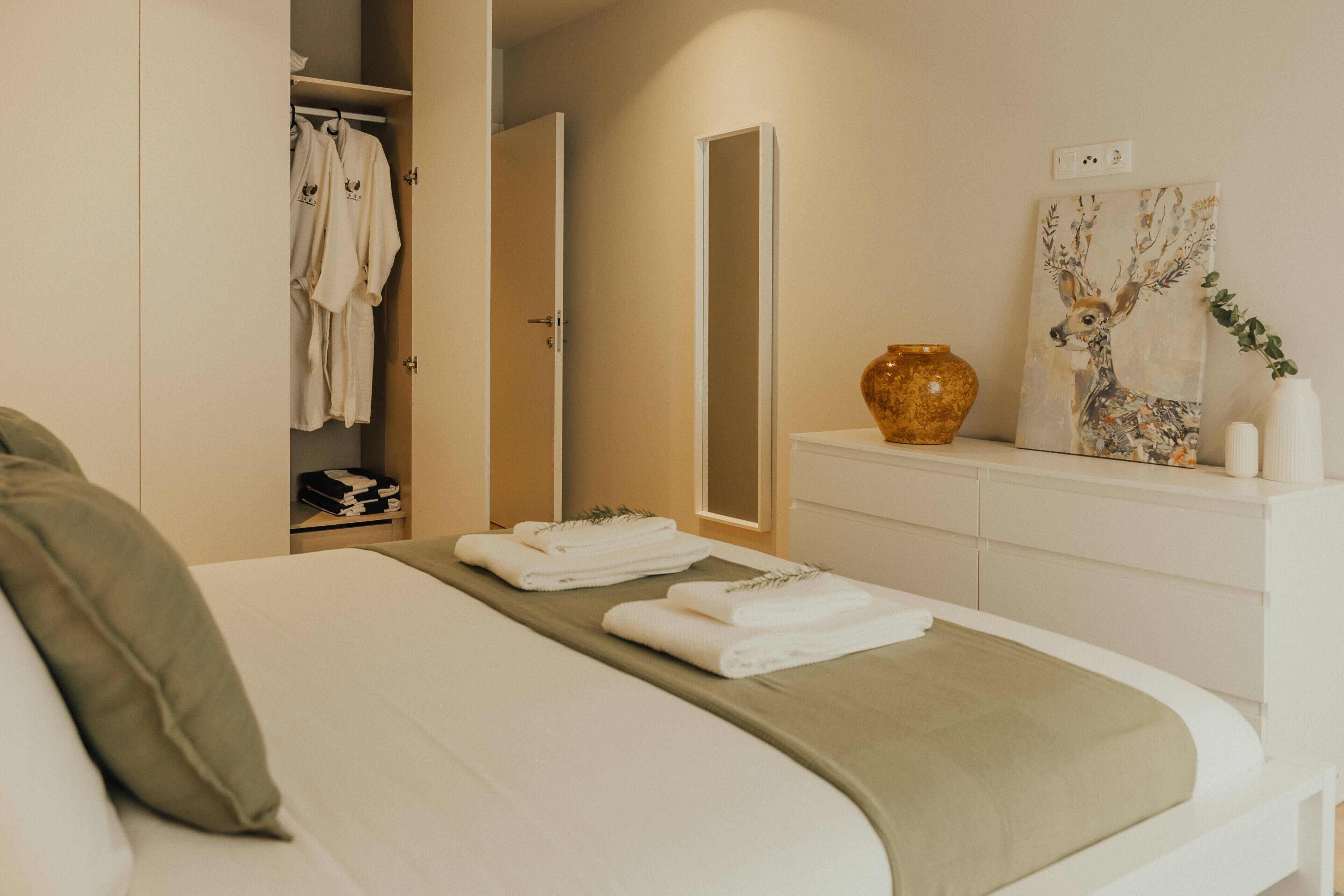 Een hotelkamer met een bed, een garderobe, een spiegel, een vaas en een schilderij.
