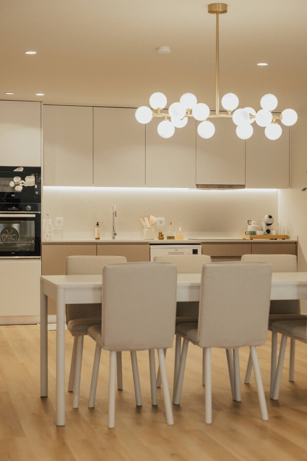 Una cocina moderna con una mesa de comedor y sillas, un horno empotrado y una lámpara colgante.