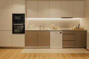 Une cuisine moderne équipée d’un four, d’un micro-ondes et d’un lave-vaisselle intégrés.