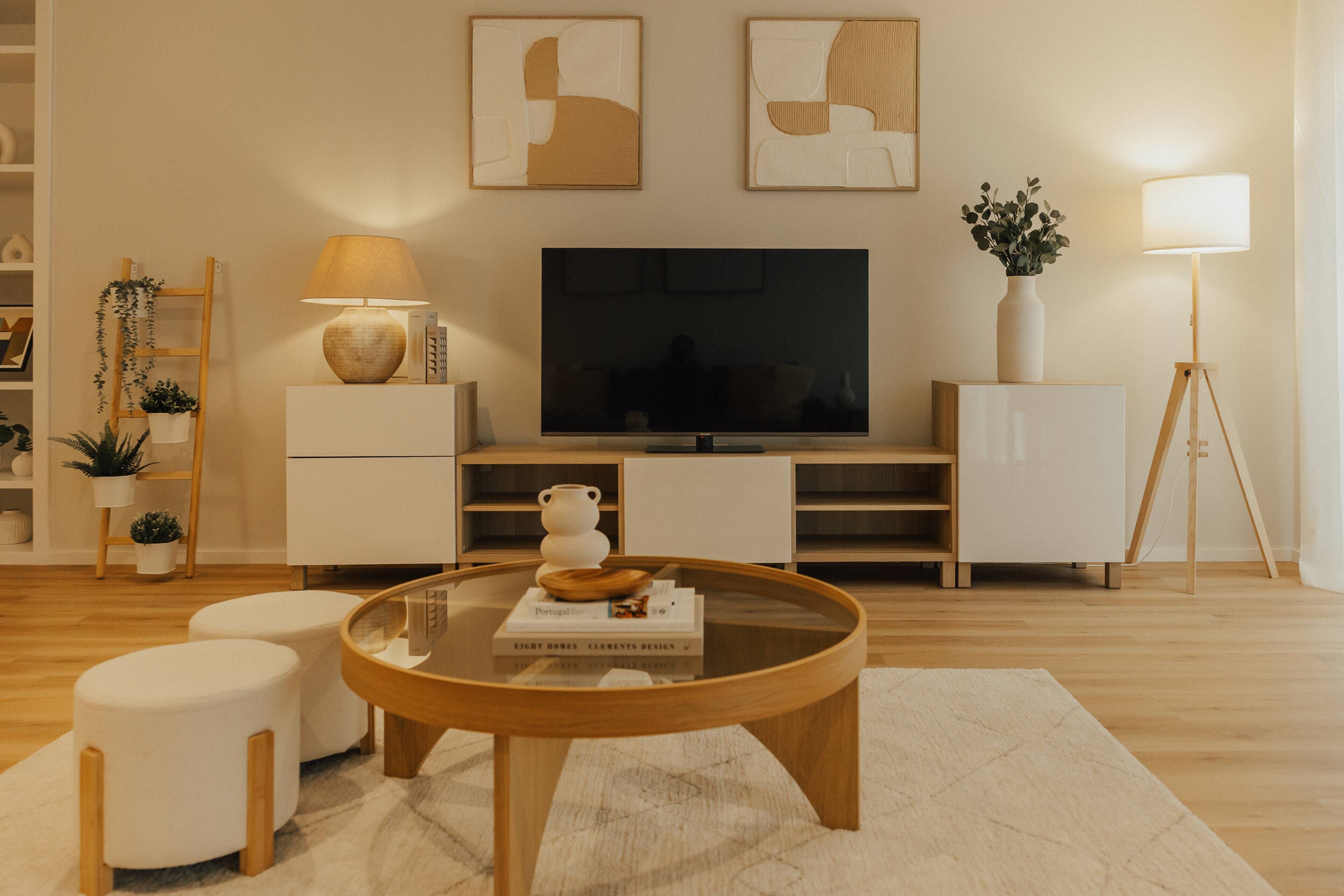 A modern living room with a flat-screen TV, a wooden coffee table, and a white sofa.