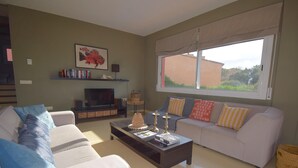 Ein Wohnzimmer mit einer Couch, einem Couchtisch, einem Fernseher und einem Fenster mit Blick.