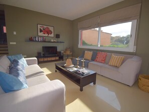 Ein Wohnzimmer mit einer Couch, einem Couchtisch, einem Fernseher und einem Fenster mit Blick.