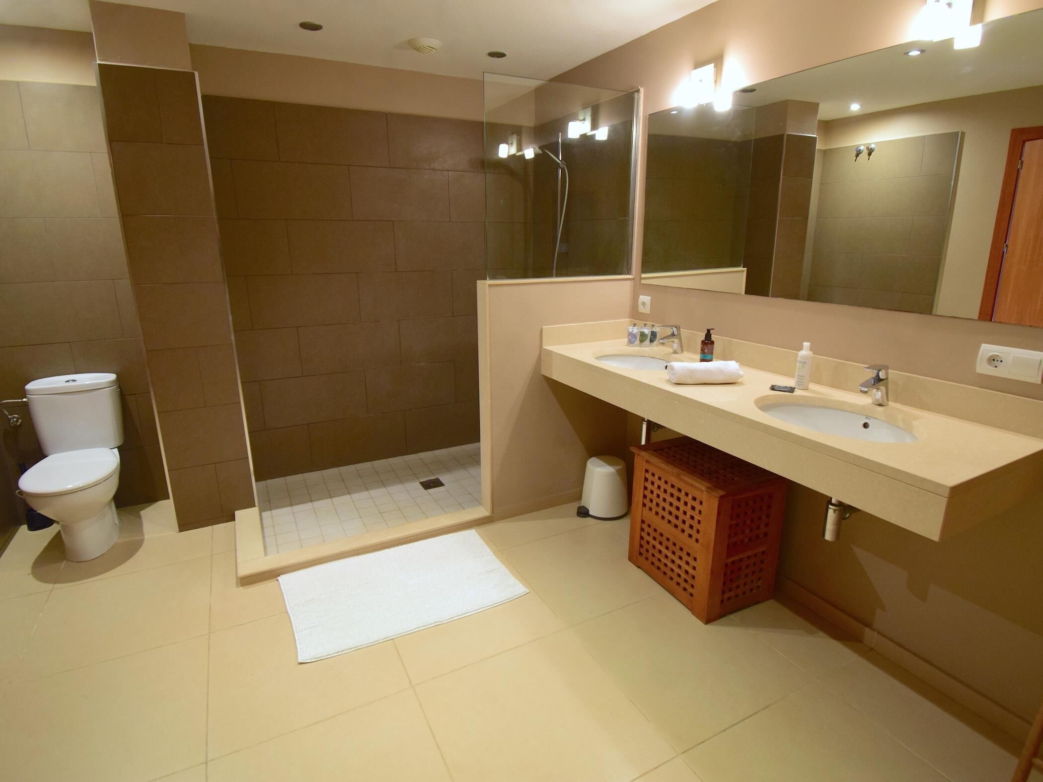 Een badkamer met twee wasbakken, een toilet, een douche en een spiegel.